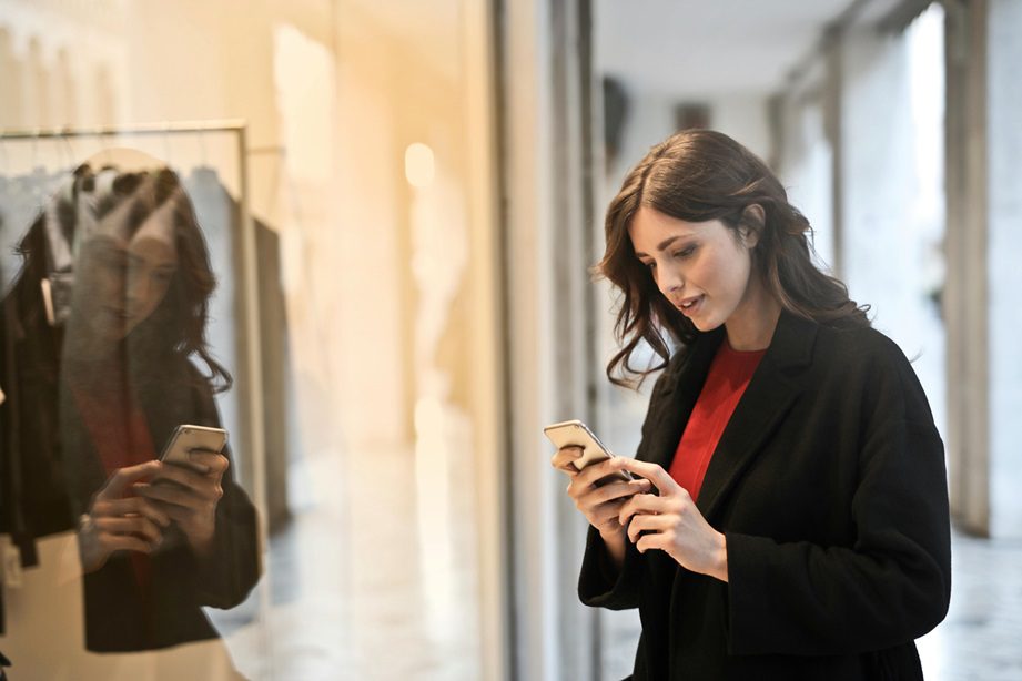 A lady uploading a mystery shopper survey on her phone after visiting a retail store